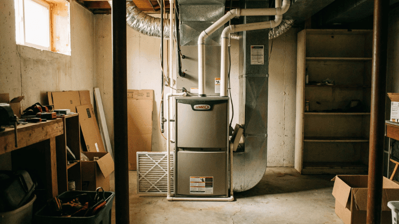 Residential furnace installed in a basement with connected ductwork and venting, providing whole-home heating and airflow.